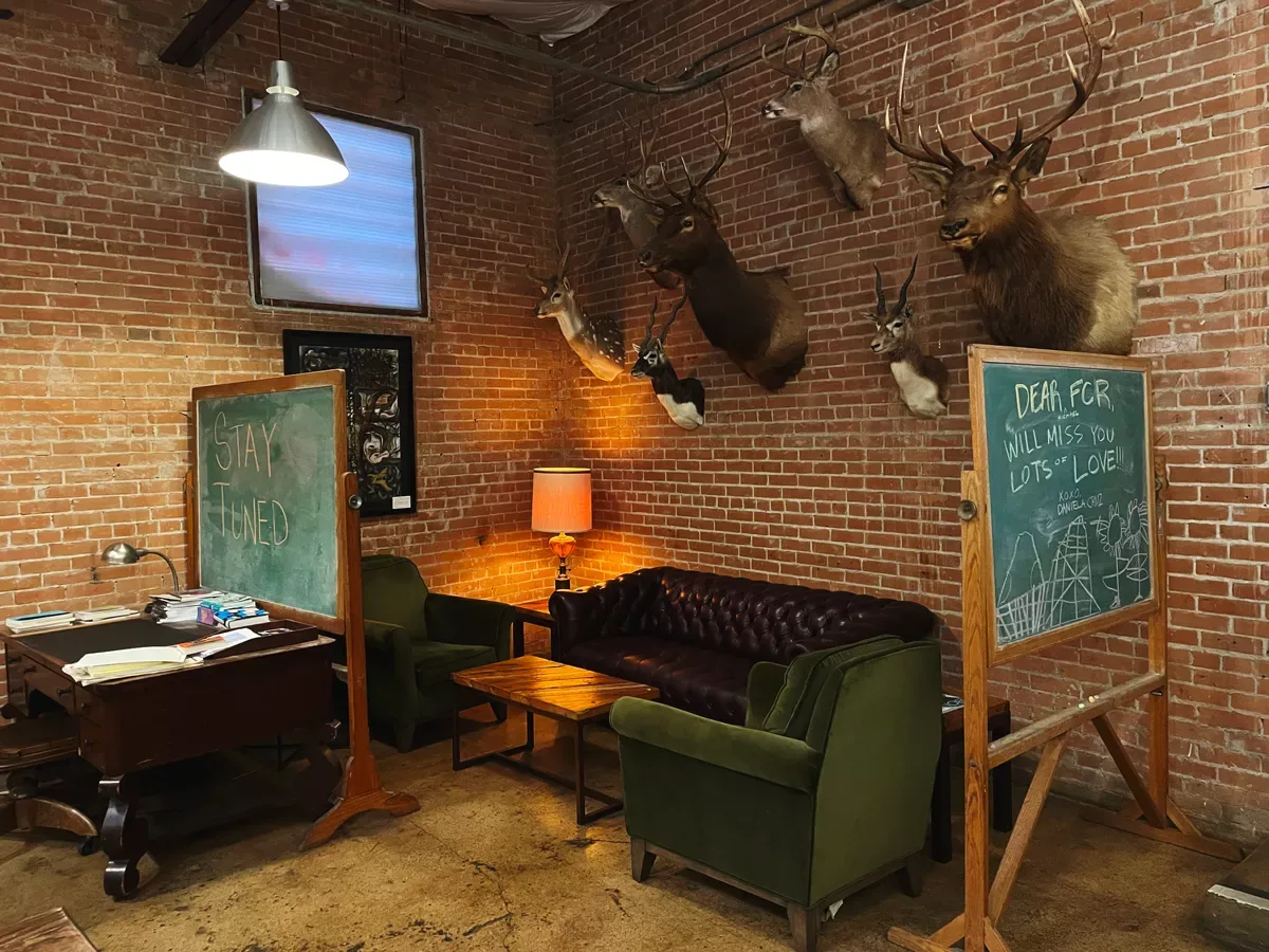 brick room with taxidermied deer heads, green chairs, chalkboards, and vintage decor., full city rooster coffee roasting stud