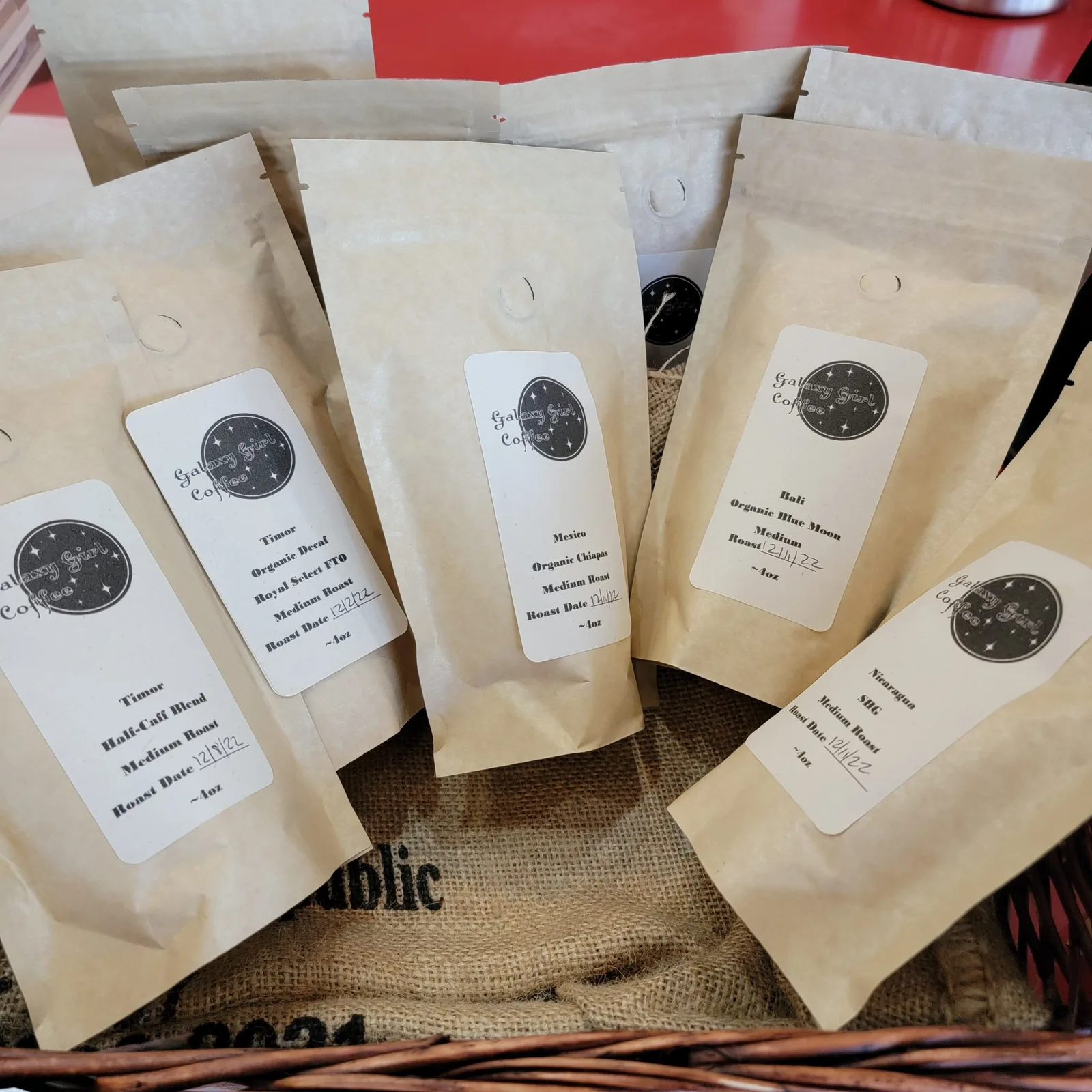 five kraft coffee bags with circular logos arranged on burlap fabric., galaxy girl coffee, llc, manhattan