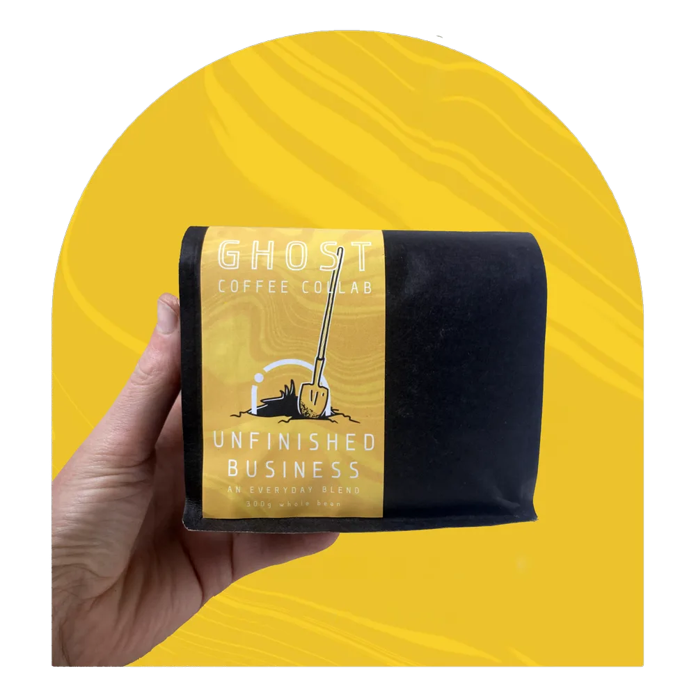 hand holding ghost coffee co's unfinished business blend against yellow background., ghost coffee collab, pittsburgh