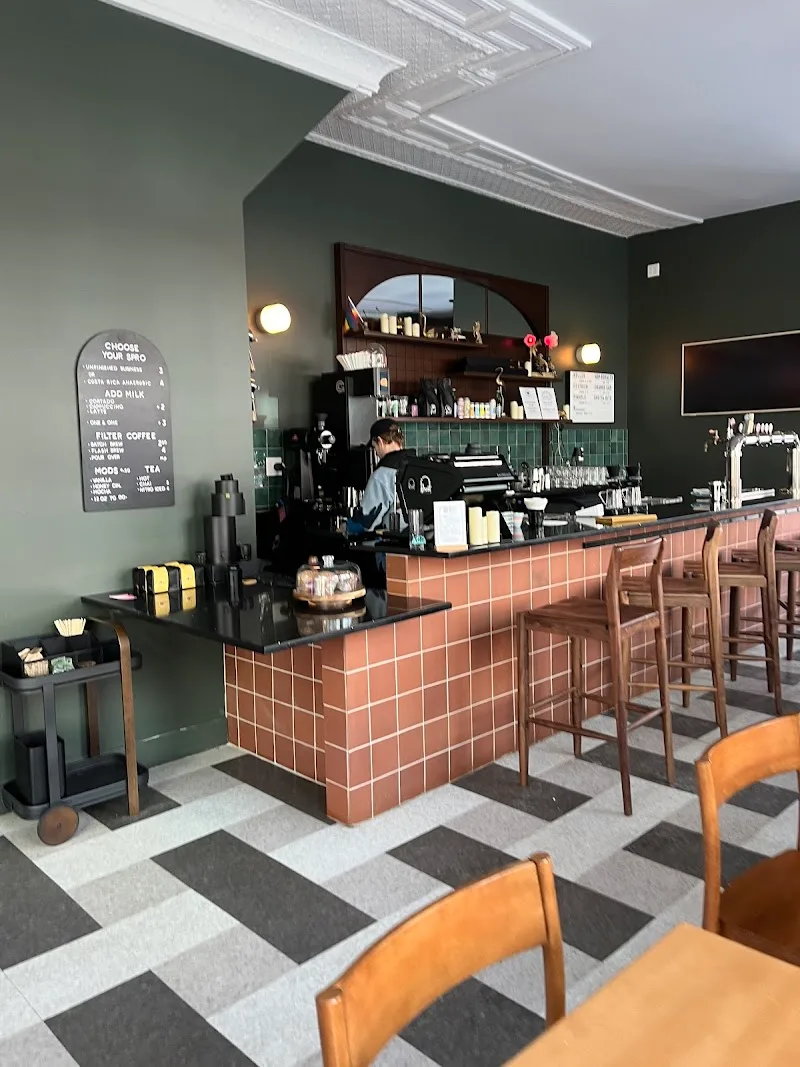 modern café interior with terracotta tile counter, sage green walls, geometric flooring., ghost coffee collab, pittsburgh
