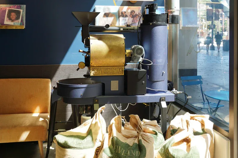 industrial coffee roaster with burlap sacks in sunlit café storefront., goldchild coffee roasters, san diego