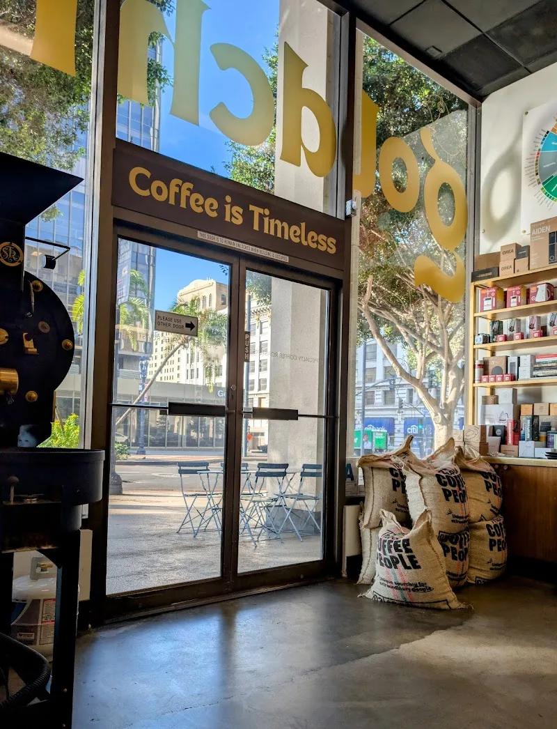 coffee shop storefront with "coffee is timeless" signage and burlap bags inside., goldchild coffee roasters, san diego