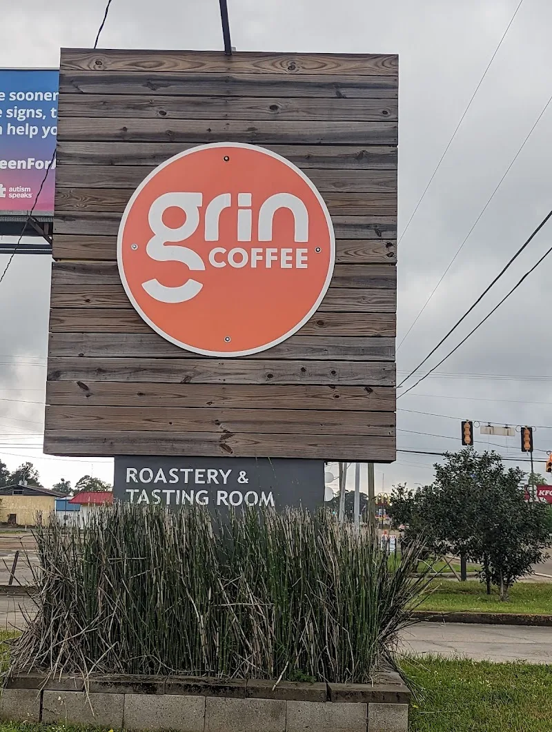grin coffee roastery and tasting room wooden sign with coral circular logo., grin coffee roastery, mississippi