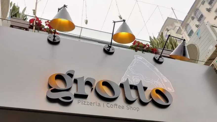 pizzeria and coffee shop storefront with illuminated signage and hanging pendant lamps., grotto - pizzeria|coffee shop, gurug