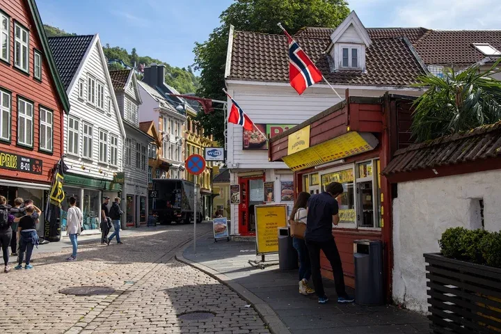 norwegian coastal village street with traditional buildings and norwegian flags., hallaisen ice cream & desserts, bergen