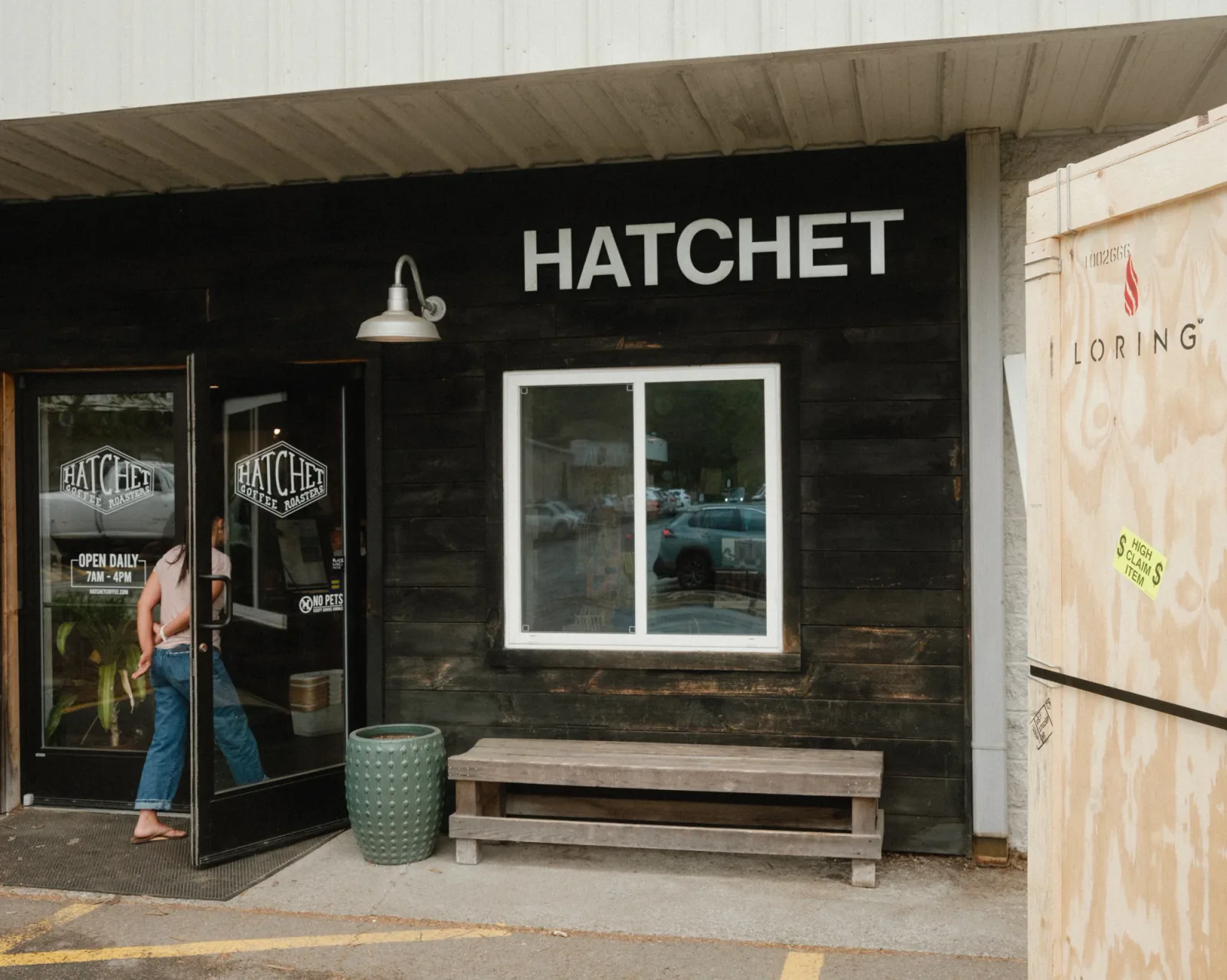 black storefront with "hatchet" signage, wooden bench, and green ceramic planter outside., hatchet coffee, boone