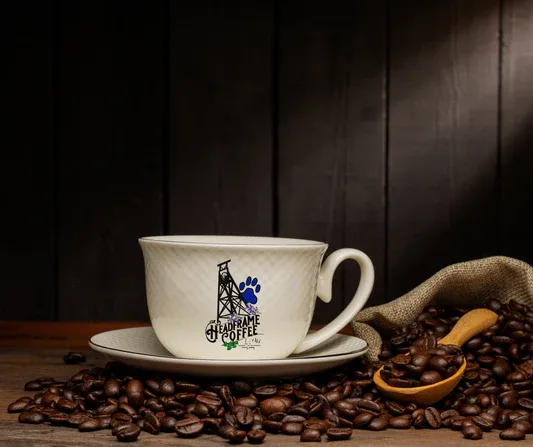 vintage coffee cup with saucer, scattered beans, and burlap sack on wooden table., headframe coffee, ely