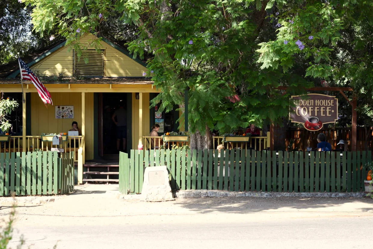 historic yellow cottage with green picket fence and hidden house coffee sign., hidden house coffee roasters, san juan capistr