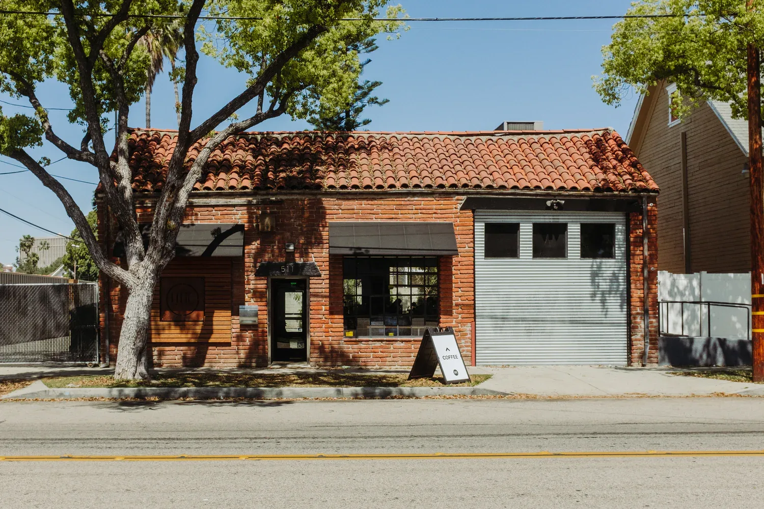 brick coffee shop with spanish tile roof and large shady tree out front., hidden house coffee roasters, san juan capistrano