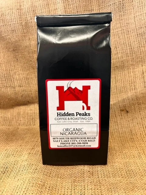 black coffee bag with red hidden peaks logo on burlap surface., hidden peaks coffee and roasting company, salt lake city