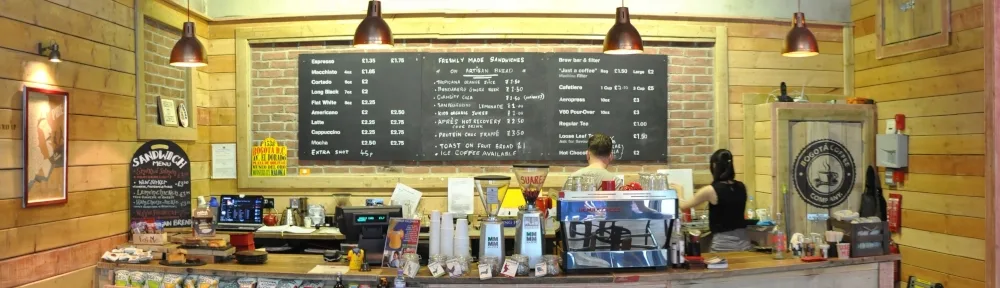 coffee shop counter with menu board, pendant lights, and barista behind register., iconico café, bogotá