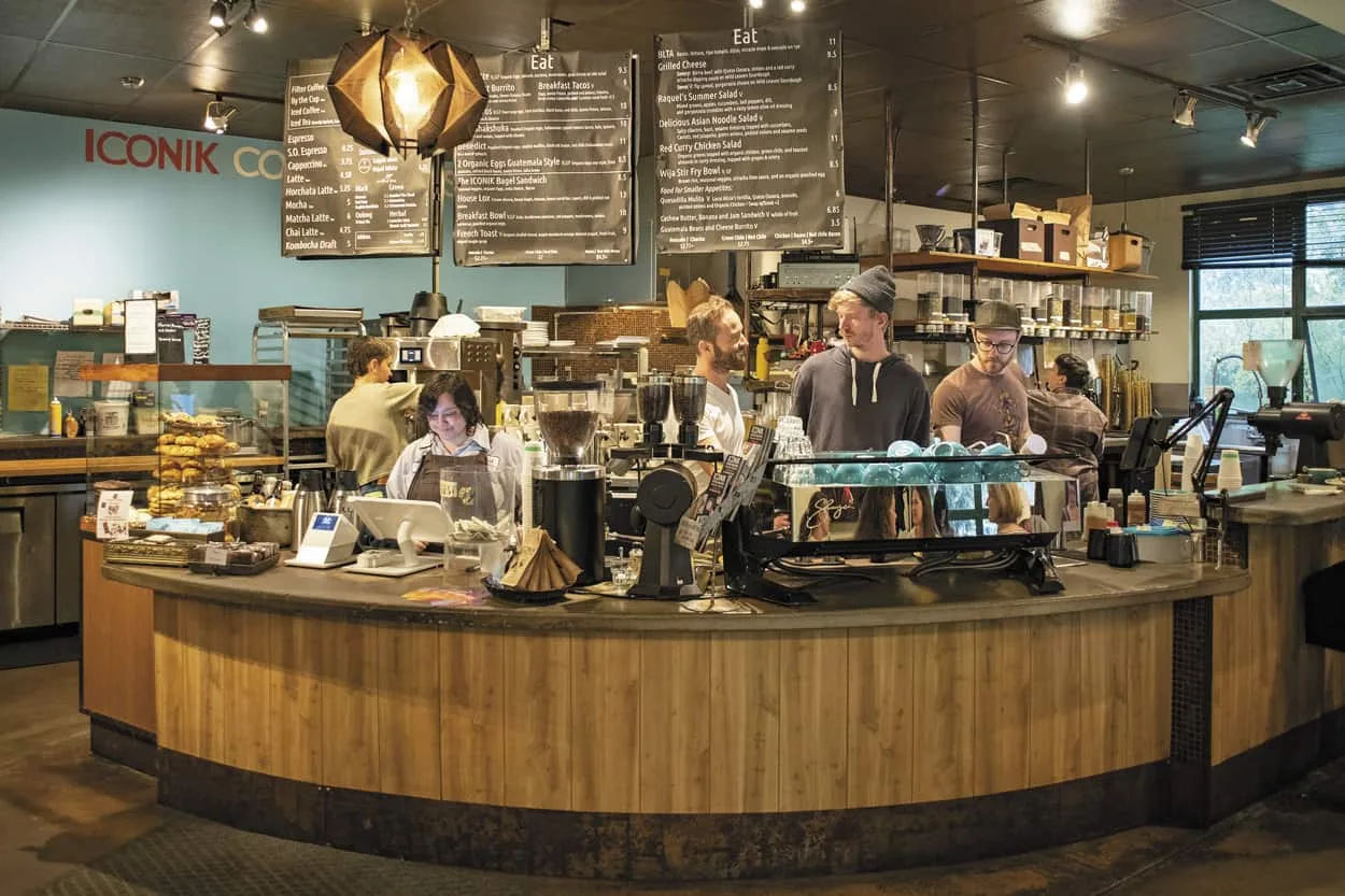 modern coffee shop interior with curved wooden counter and baristas preparing drinks., iconik coffee roasters, santa fe