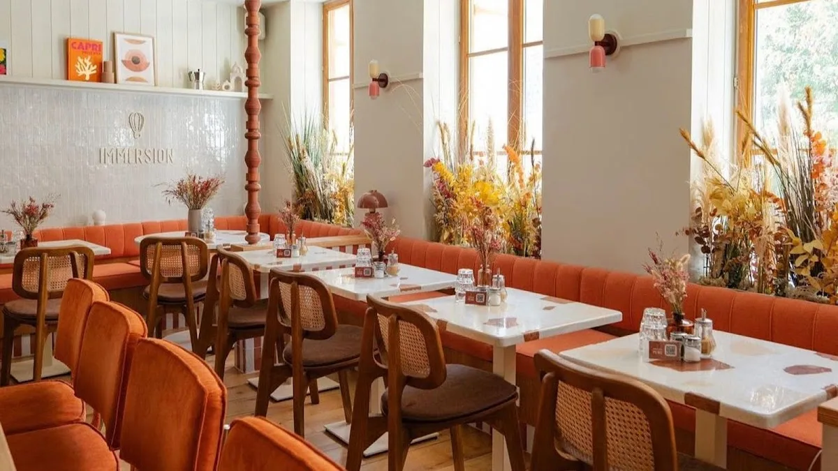modern restaurant interior with orange seating, wooden chairs, dried flowers, and natural light., immersion sentier - brunch 