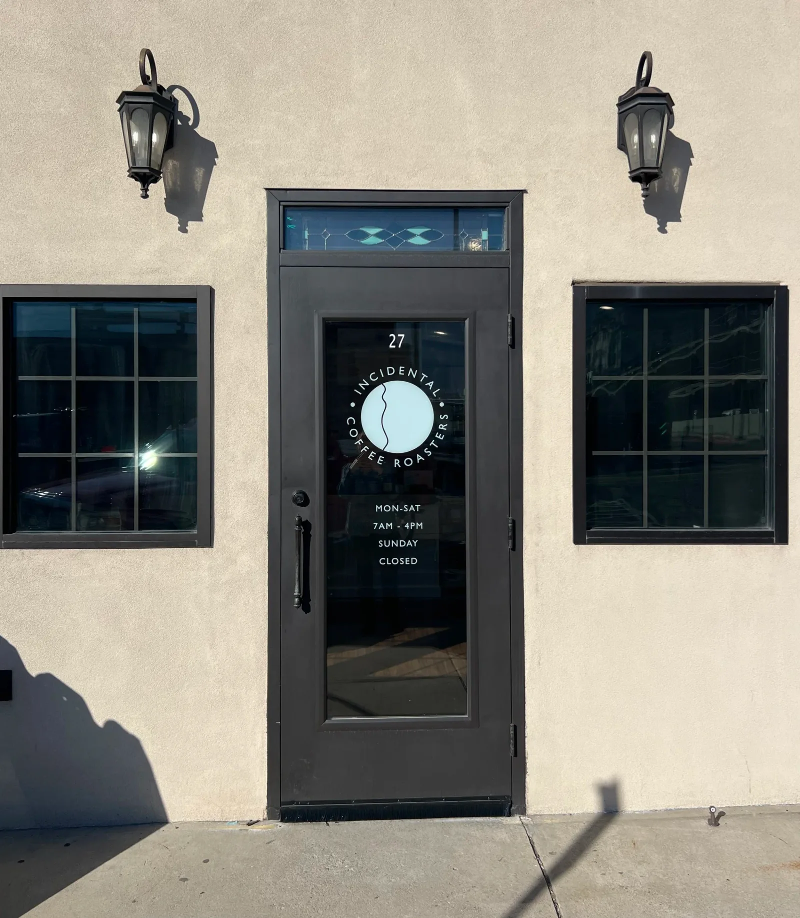 storefront entrance for incidental coffee roasters with symmetrical windows and wall sconces., incidental coffee roasters, pr
