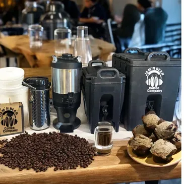 coffee equipment display with beans, grinders, brewing devices, and ginger root on wooden table., jam 'n bean coffee company,