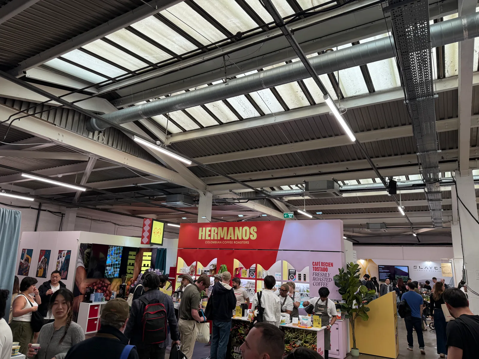 the hermanos colombian coffee roasters booth at london coffee festival 2026, with crowds shopping at the festival