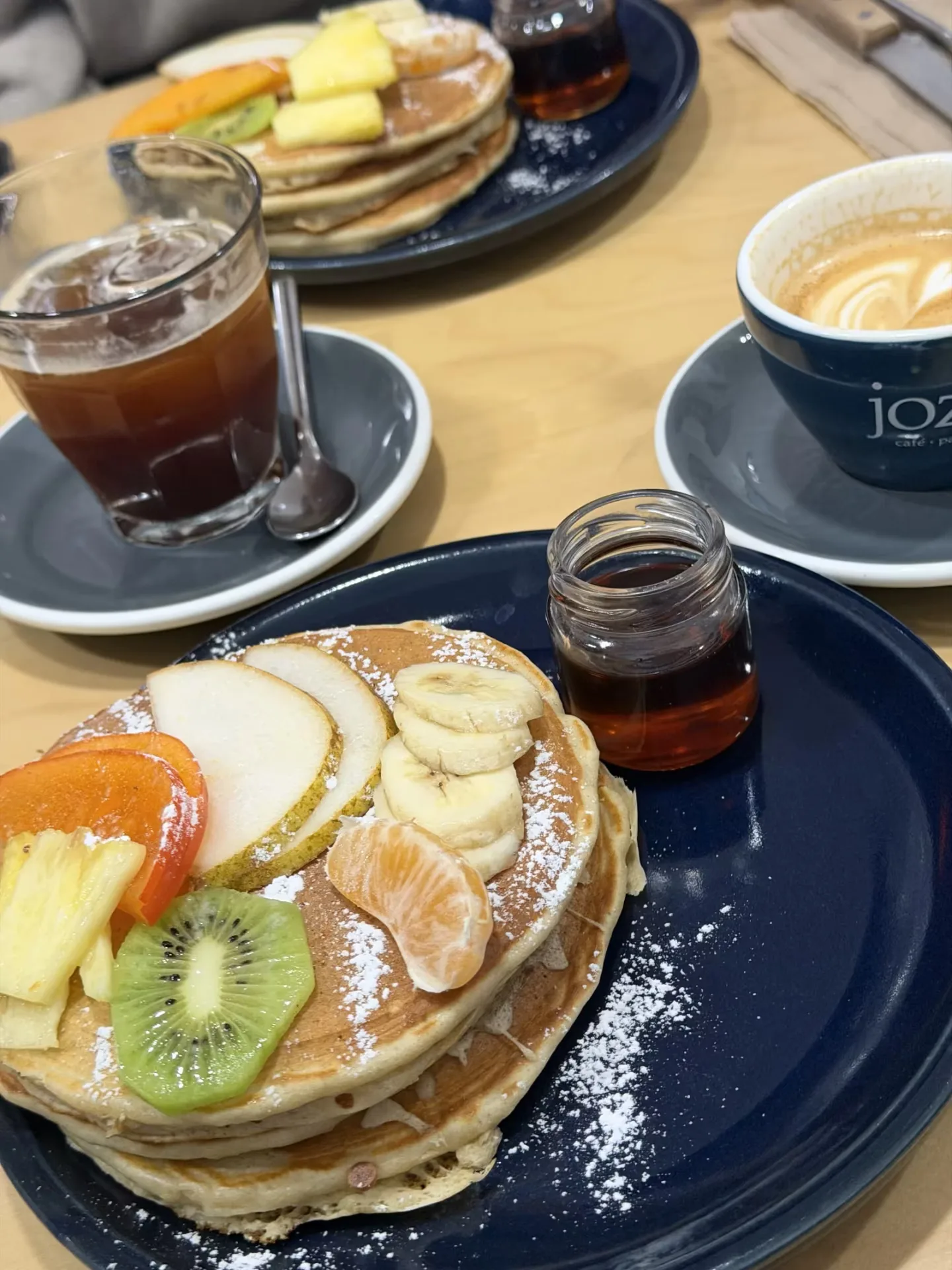 breakfast table with fruit pancakes, iced coffee, and latte art cappuccino., jozi brunch, paris