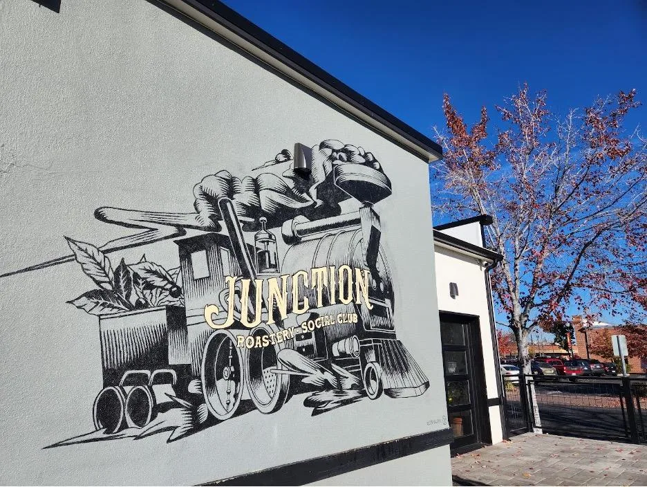 black and white mural of vintage train with "junction roastery & craft club" text on white wall., junction coffee, redmond