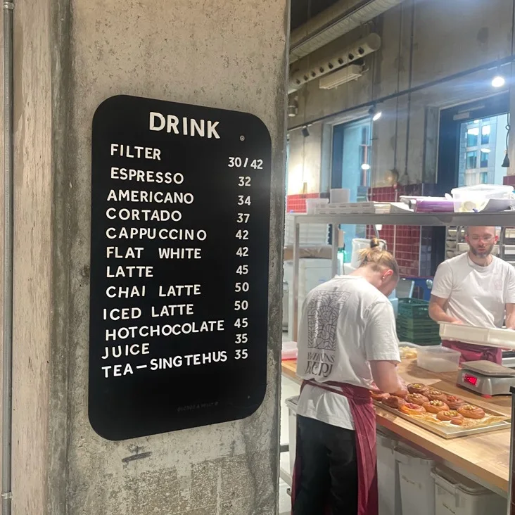 black menu board displaying coffee drinks and prices on café wall., københavns bageri, copenhagen