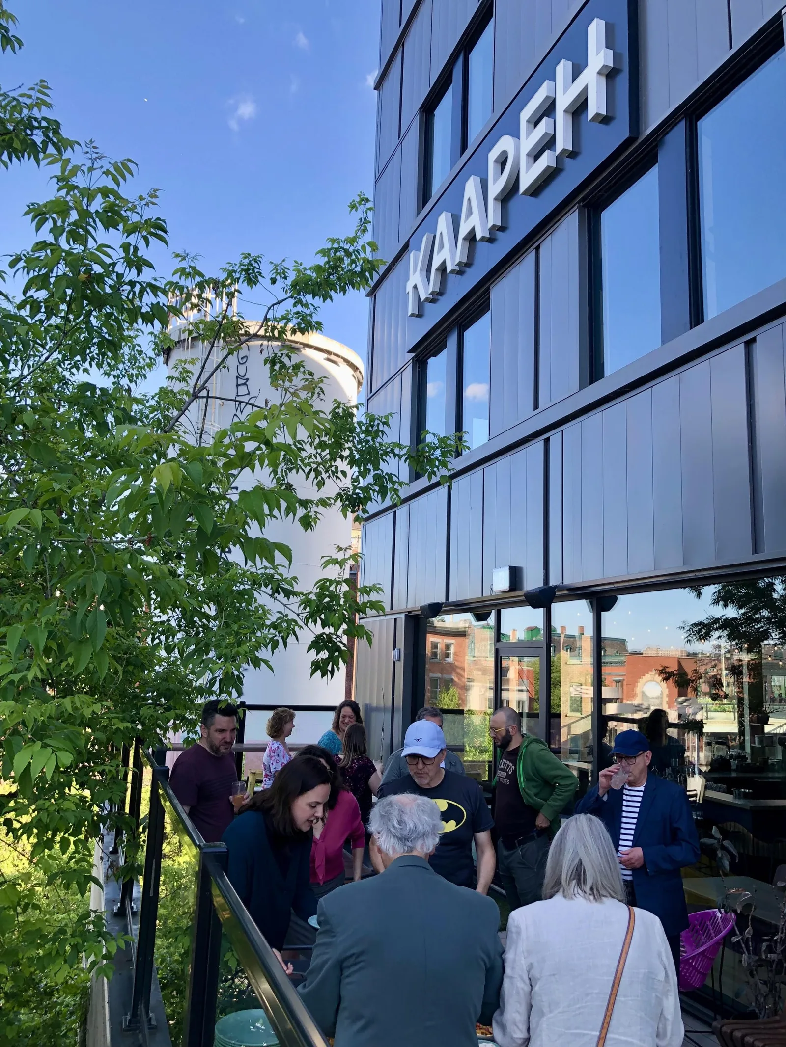 group of people gathered outside modern building with "kaaperi" signage, sunny day., kaapeh, sherbrooke