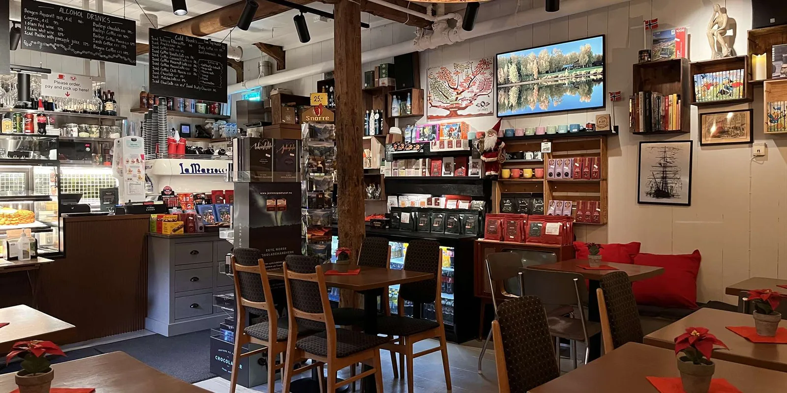 cozy café interior with wooden beams, red accents, shelving, and dining tables., kaf kafe bryggen, bergen