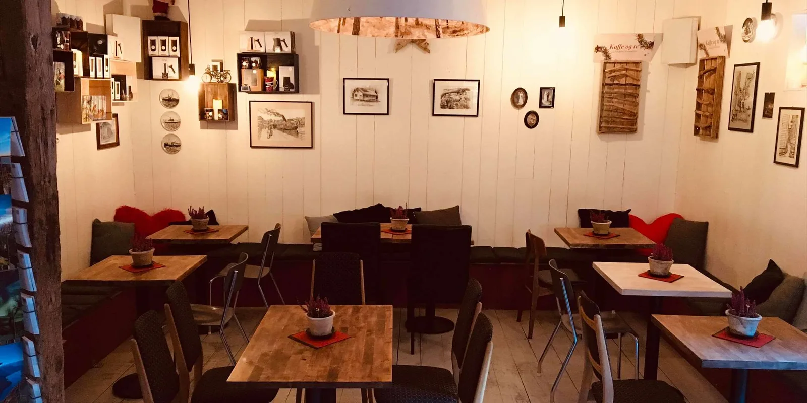 cozy café interior with wooden tables, black chairs, and gallery wall art., kaf kafe bryggen, bergen