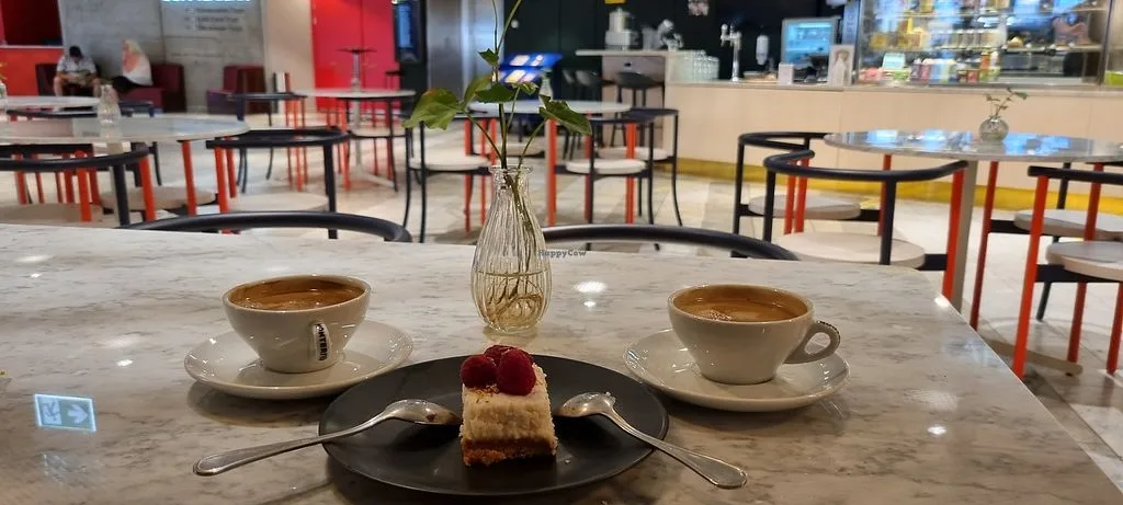 two coffees, pastry with rose, and flower vase on marble table., kafé plattan, stockholm
