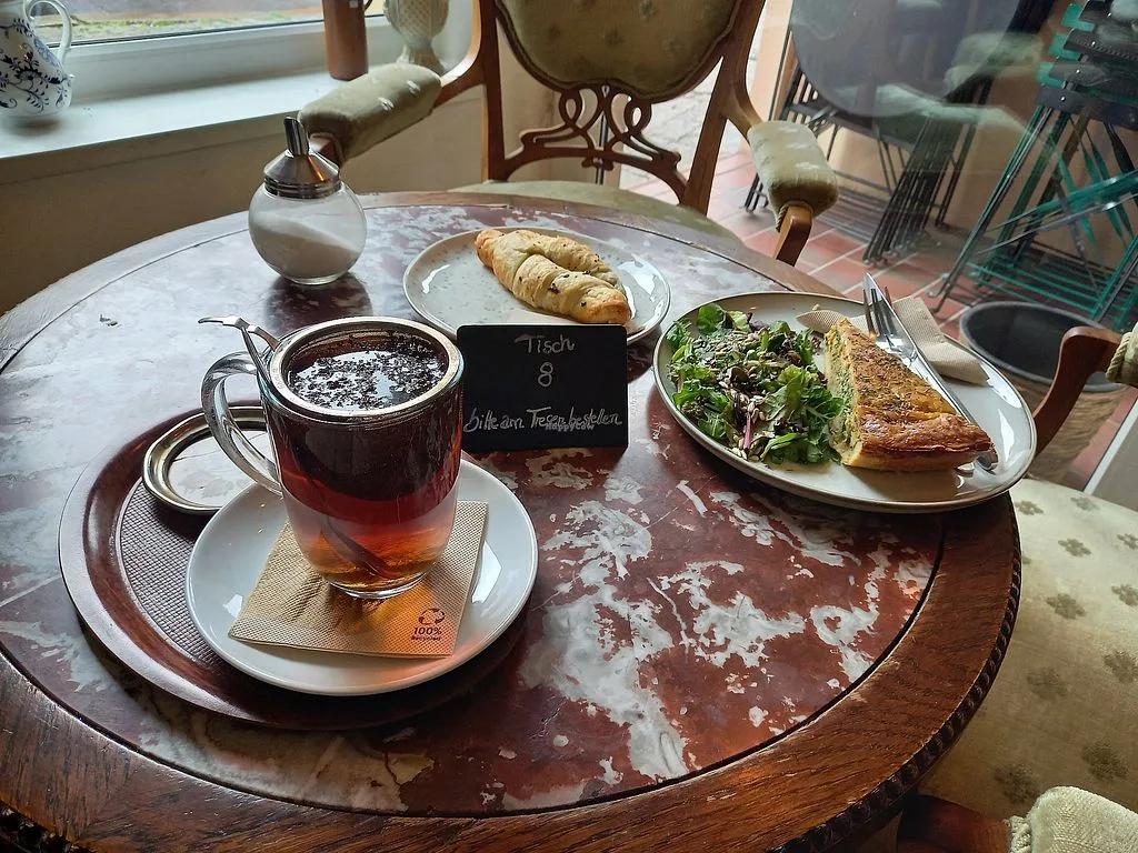 tea service with croissants, sandwiches, and salad on round wooden table., kaffee 26, berlin