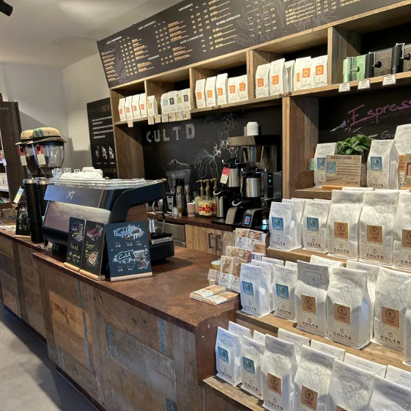 coffee shop counter with packaged beans, espresso machine, and menu board., kaffeerösterei coffee unlimited, hamburg
