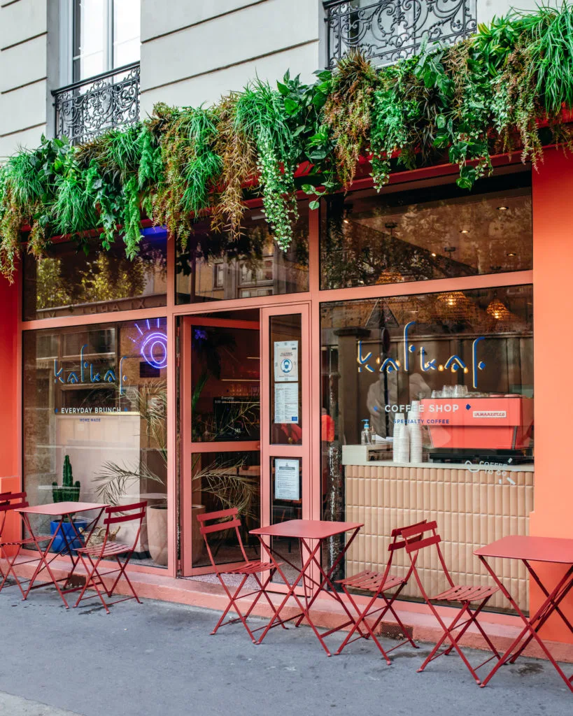 modern coral coffee shop with hanging plants and red outdoor seating furniture., kafkaf, paris