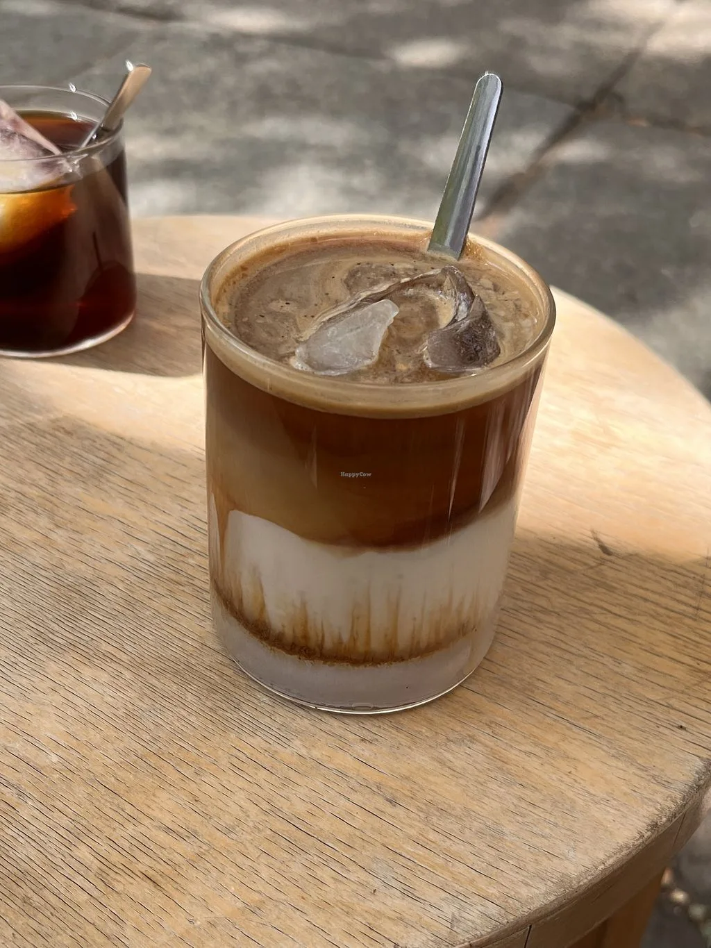 iced coffee with cream layered in glass on wooden table outdoors., kajumi, berlin