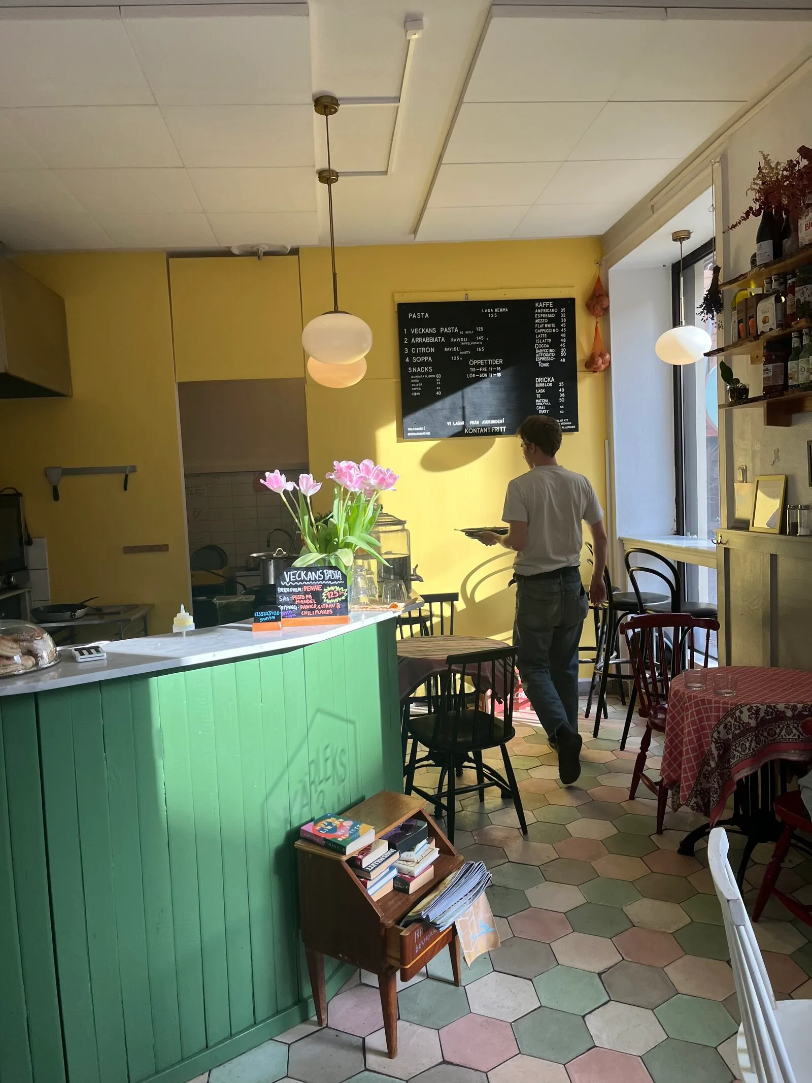 cozy café interior with yellow walls, green counter, and pink flowers on display., kärleksgatan 3, malmö
