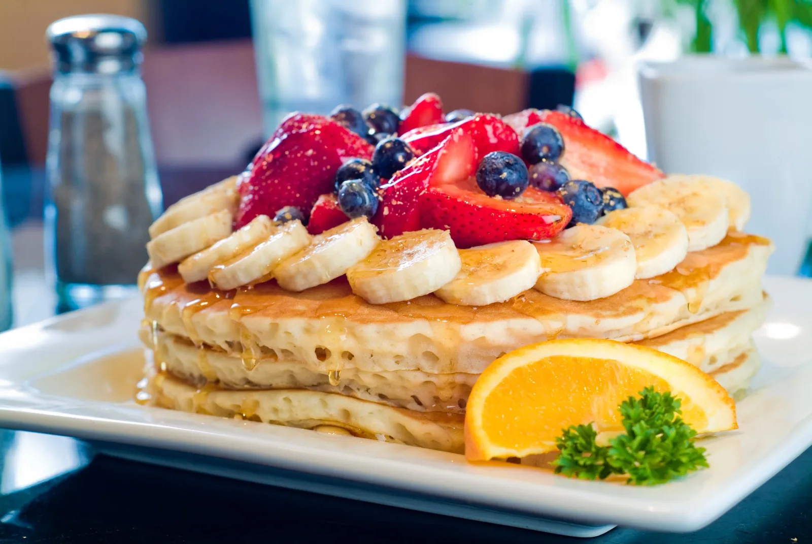 layered pancakes topped with berries, banana slices, and caramel sauce., keke's breakfast cafe, miami