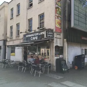 small street-level cafe with outdoor seating and historic building facade above., kennington lane cafe, london