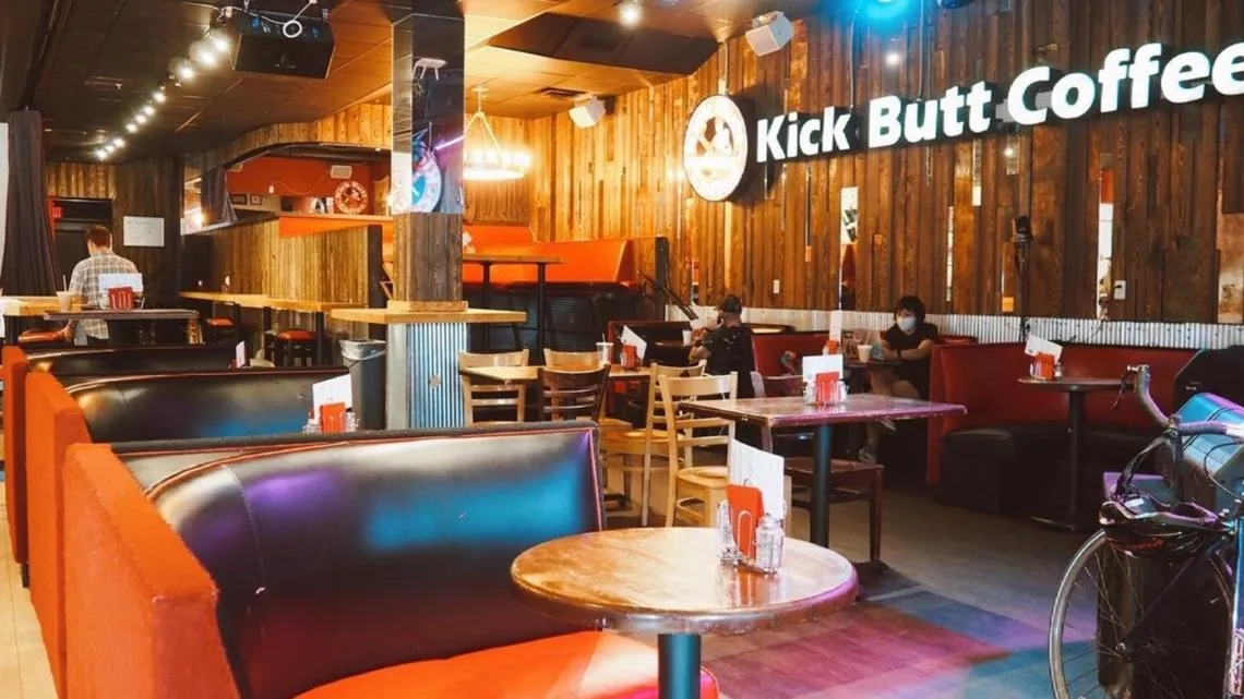 kick butt coffee shop interior with wooden walls, orange seating, and customers., kick butt coffee, austin