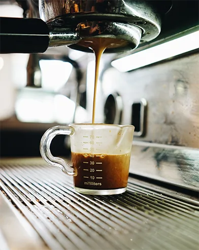 espresso pouring into glass measuring cup from machine portafilter., kindred coffee co., north richland hills