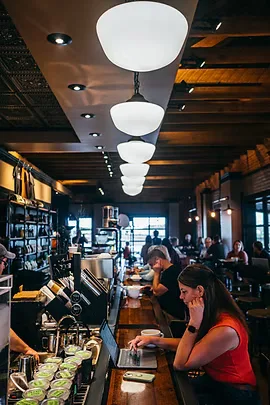 busy coffee shop interior with customers at counter, modern pendant lighting overhead., kitt's kitchen and coffee, kearney