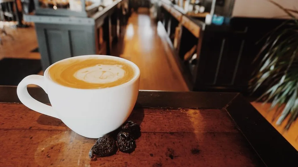 latte with latte art in white cup on wooden table, café setting., kitt's kitchen and coffee, kearney