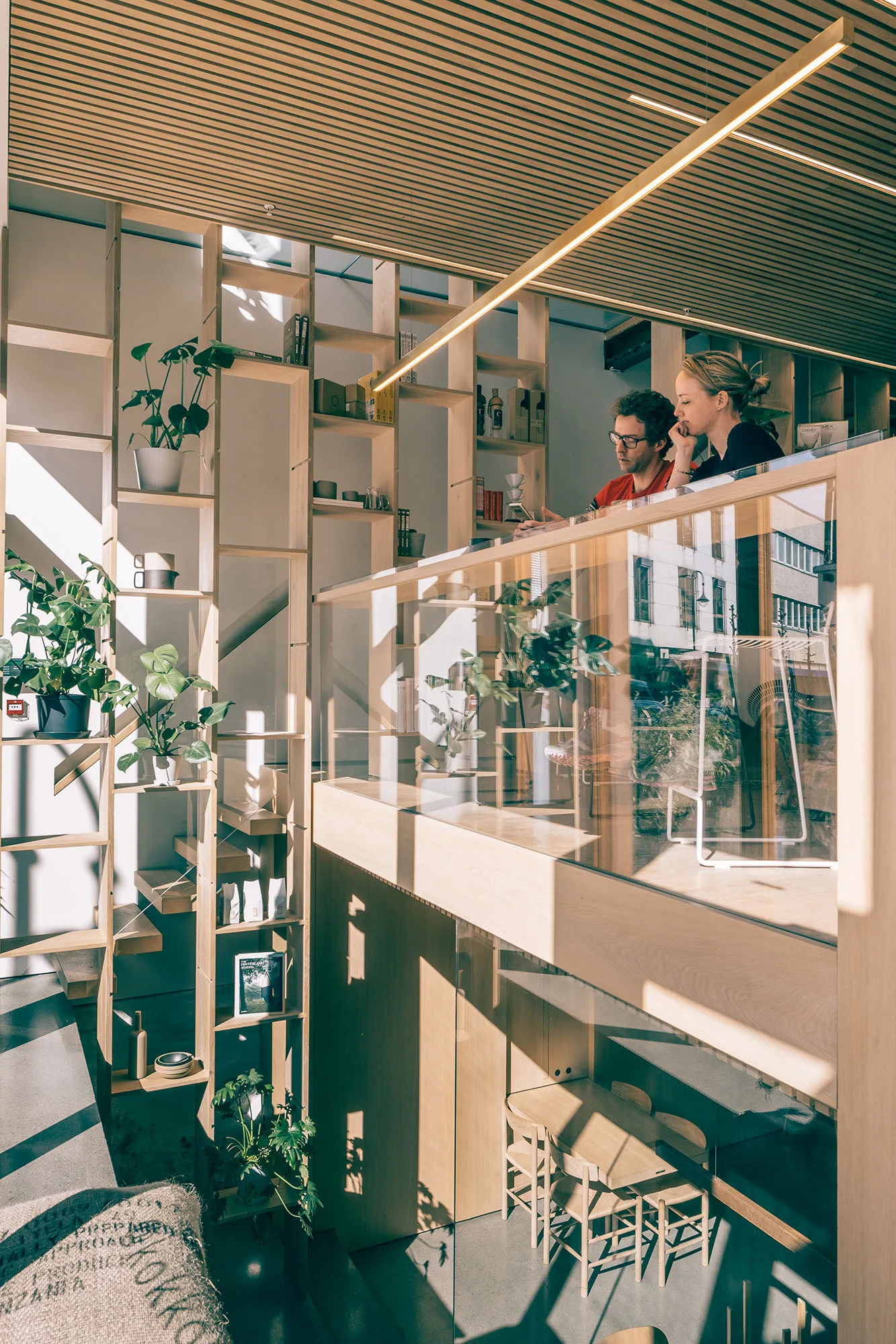 modern office loft with two workers, wooden shelving, plants, and natural light., kokko kaffebar, stavanger