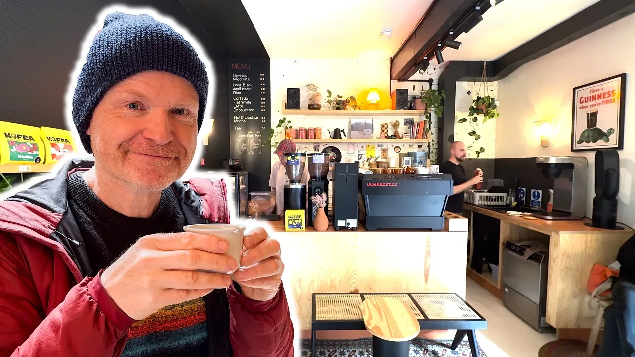 man in beanie holding cup at cozy coffee shop interior with shelving and menu board., komodo • specialty coffee brewers, brig
