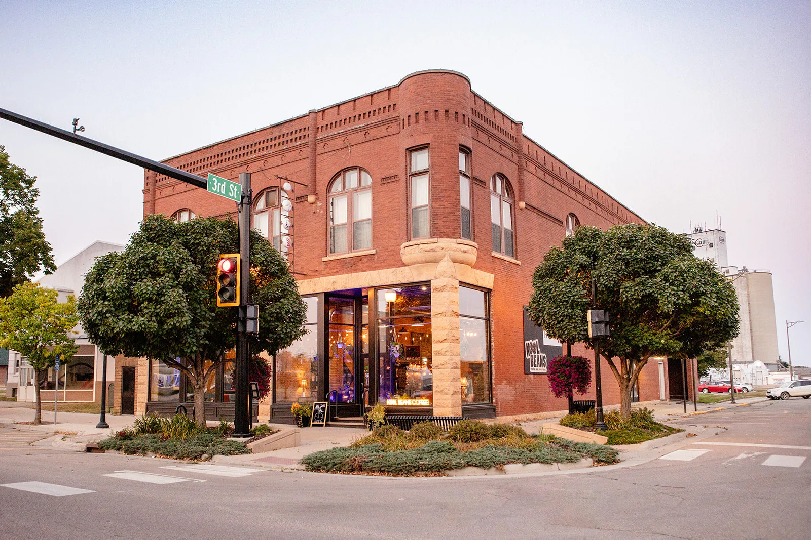 historic red brick corner building with ivy-covered trees and street signage., kool beans coffee and roasterie, brookings