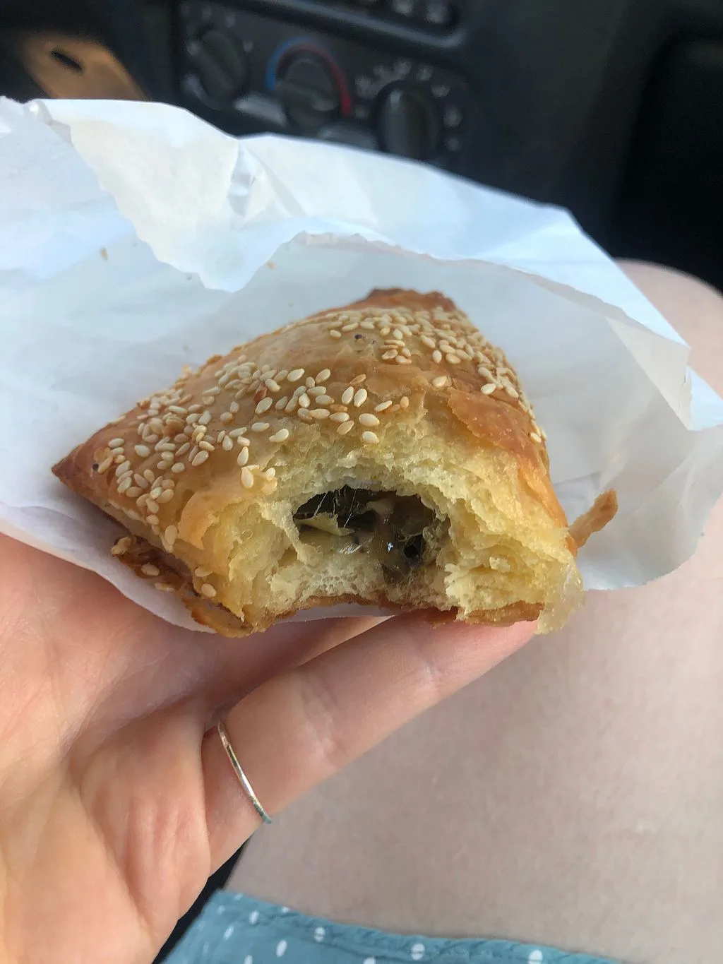 hand holding sesame seed pastry with dark leafy filling in white wrapper., kopi coffee house, portland