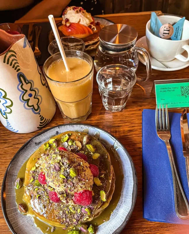 plated dessert with nuts and berries, juice drink, water glass, pastry, and table setting., kozy, paris