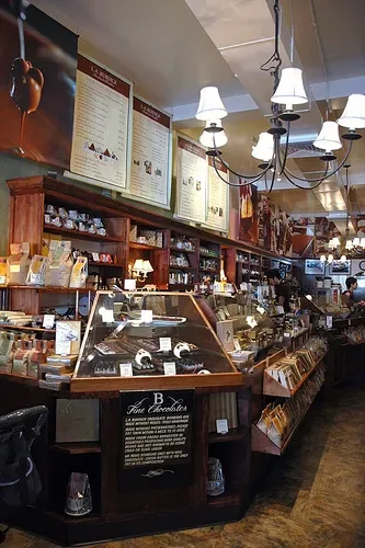 coffee shop interior with counter display cases, shelving, hanging lamps, and merchandise., la burdick, cambridge