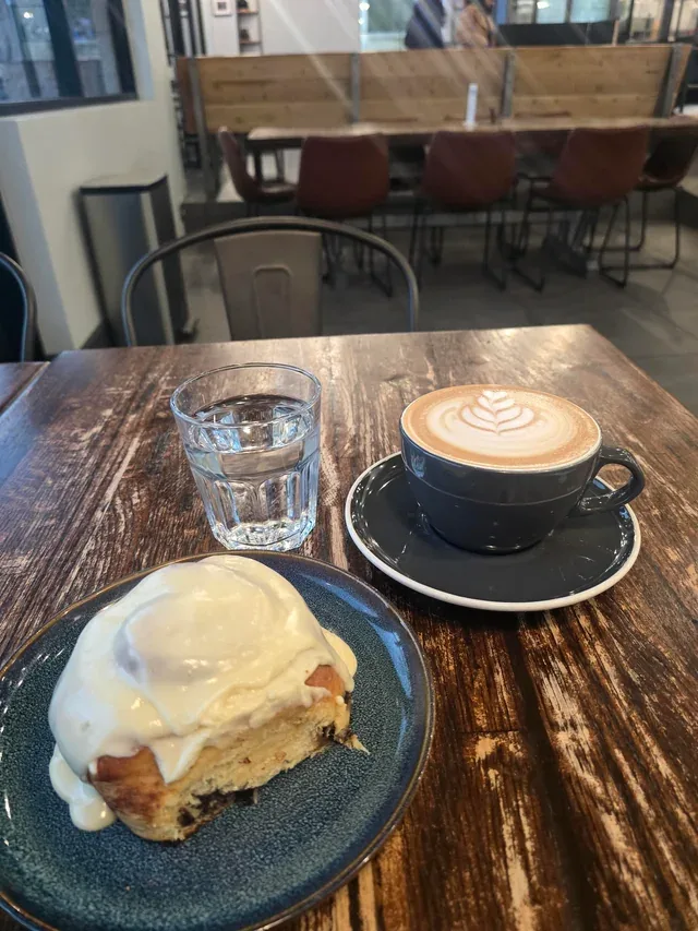 café table with pastry, latte art coffee, and water glass indoors., la finca coffee & bakery, mckinney