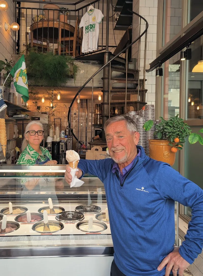 man holding ice cream cone at gelato shop counter with display case., la gelateria sofo, stockholm