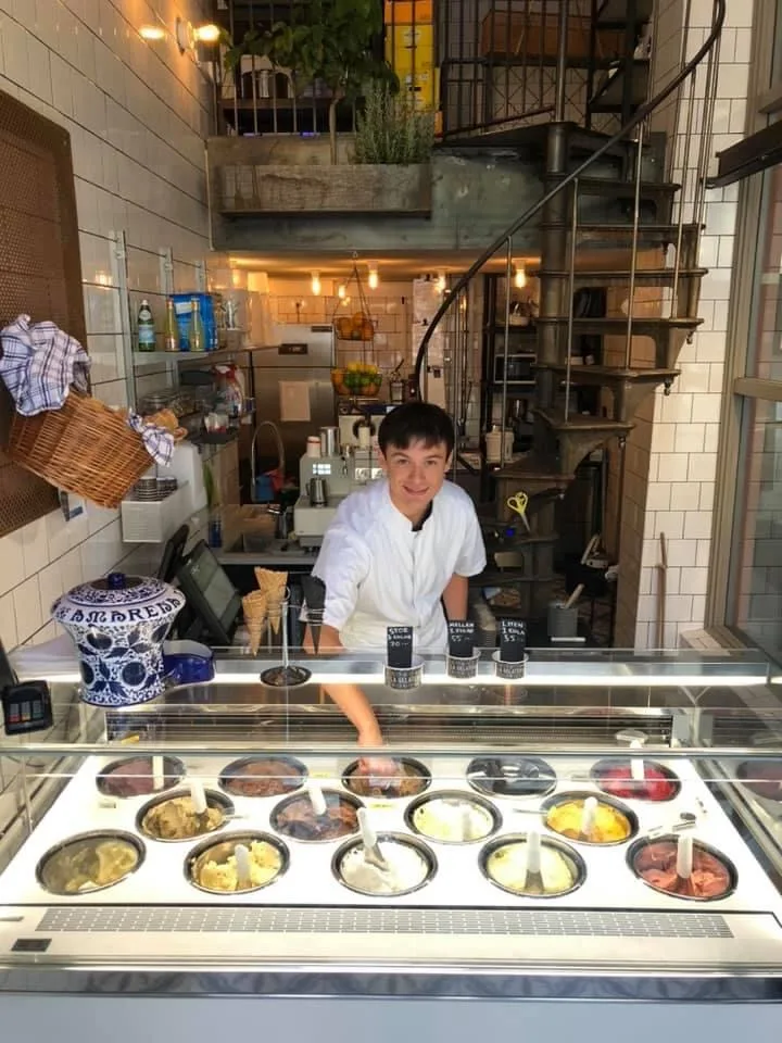 ice cream shop employee behind counter with gelato display cases and flavors., la gelateria sofo, stockholm