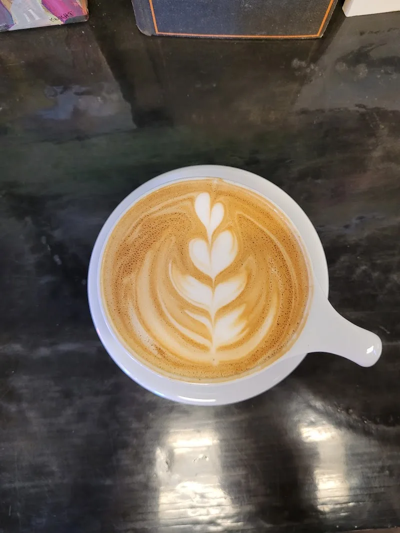latte with leaf latte art in white cup on dark table., la mulita coffee, rye