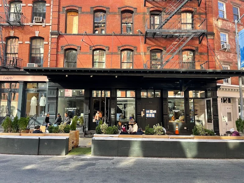 historic red brick building with black storefront and outdoor seating area., laughing man coffee, new york