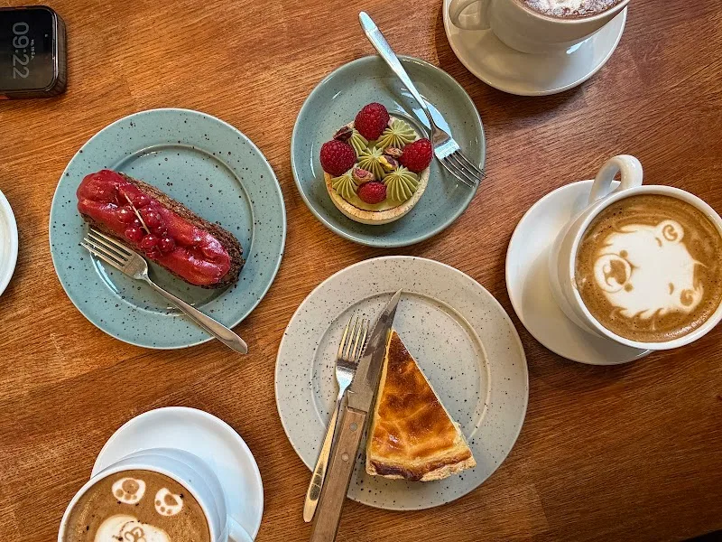 cafe table with pastries, desserts, and latte art coffees on wooden surface., le café pomme, bergen